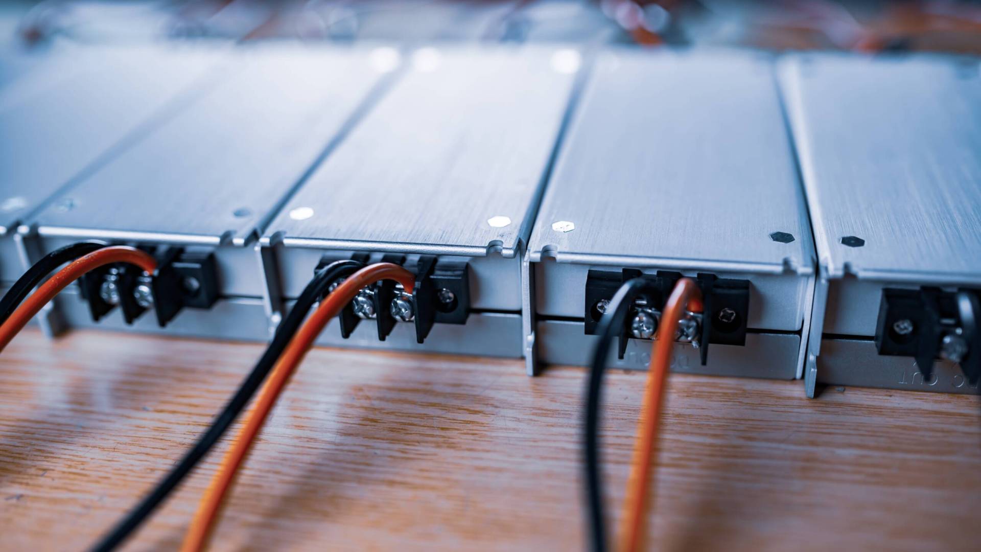 Close-up metal AC-DC power supply with wires Close-up metal AC-DC power supply with wires lie on wooden table in anticipation of further installation in the production of equipment for specialized enterprises. Concept of high-tech equipment